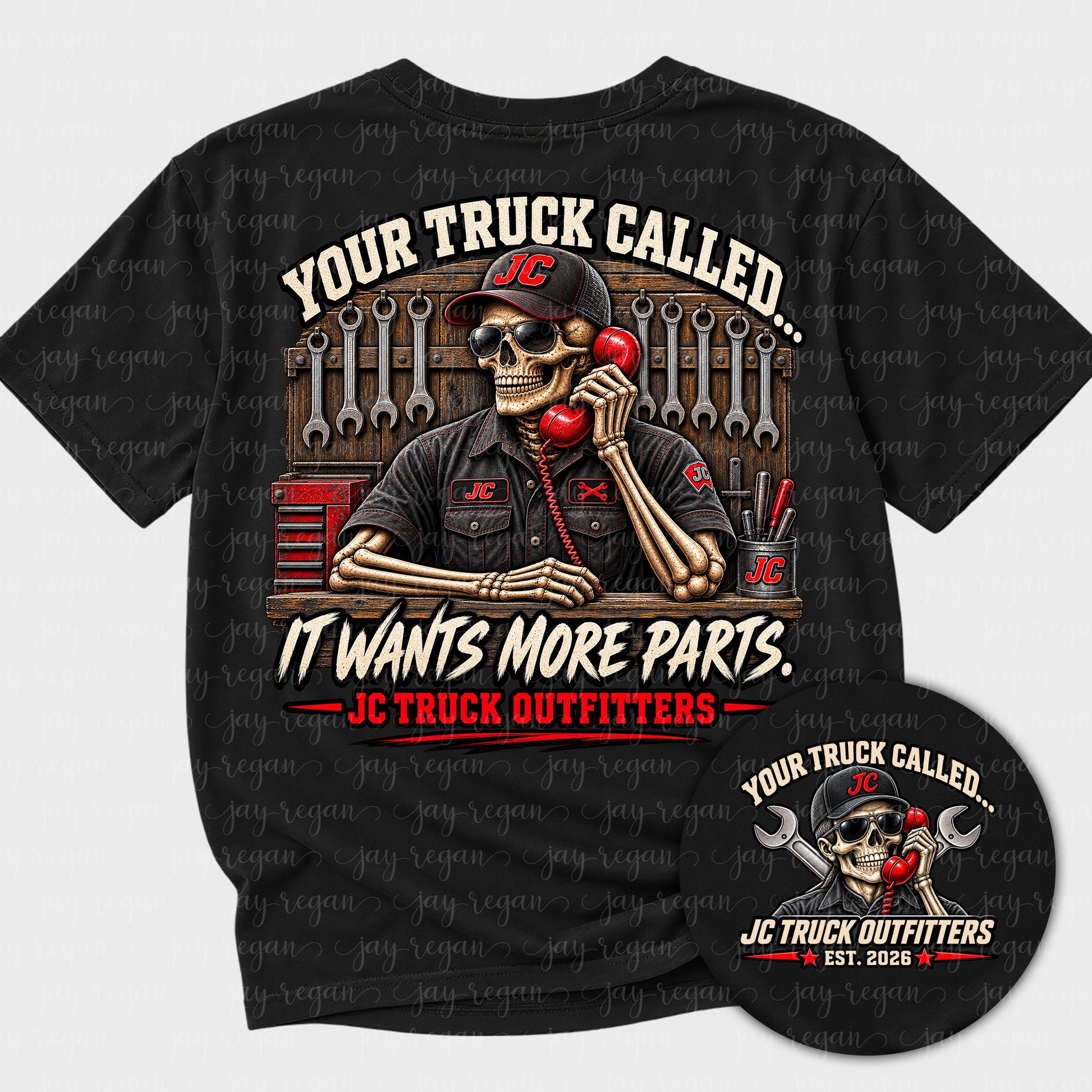 Black t-shirt with a full-back print: a skeleton in a JC cap standing at a parts counter with a red phone to his ear and a wall of wrenches behind him, reading Your truck called, it wants more parts.